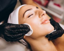 Cosmetologist cleaning face of a woman in a beauty salon